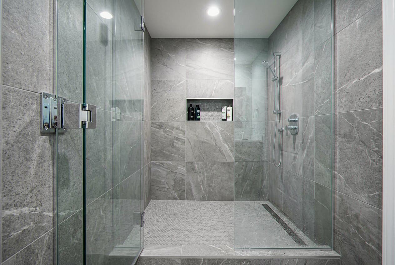 Renovated shower with gray stone-look tile and glass door